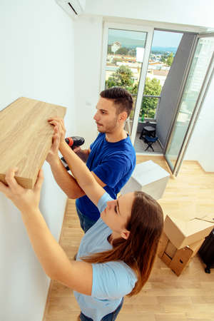 Man and woman together putting shelf in their apartmentの写真素材