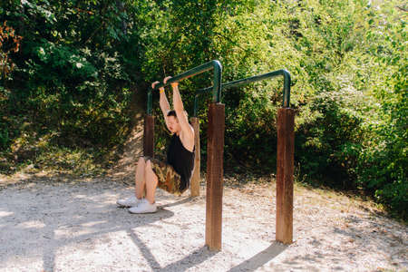 Sportive man doing pull-ups on metal bar in the forest gymの写真素材
