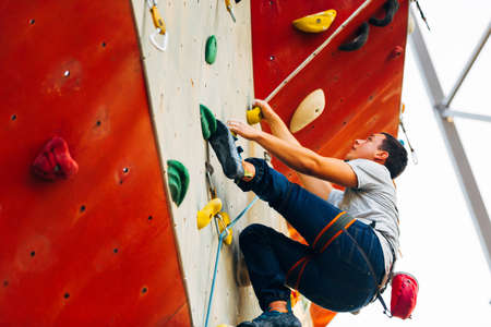 Young man practicing bouldering in outdoor climbing gymの写真素材