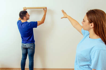 Girl show to her boyfriend where to put bookshelf in living roomの写真素材