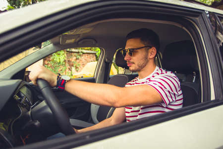 Young man sitting in his car and preparing to drive with his window openの写真素材