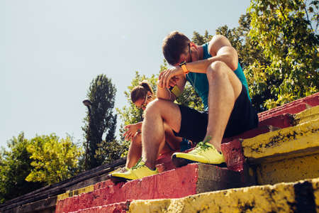 Runners in the city park resting after jogging and listening to musicの写真素材