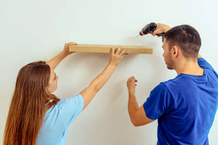 Craftsman putting book shelf while work with the drill in living roomの写真素材
