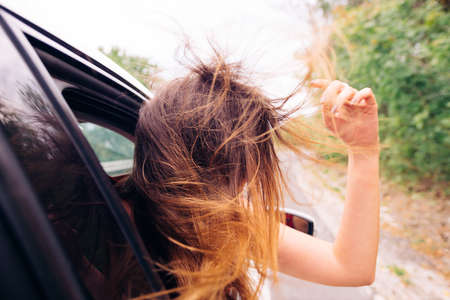 Wild girl riding around with her head out of the car window.の写真素材