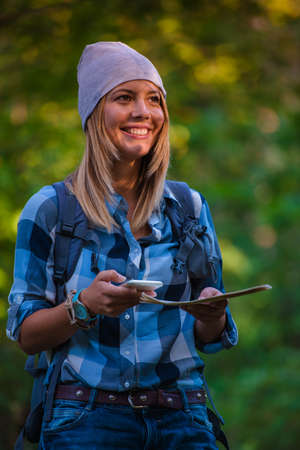 Young woman walking alone in the woods holding a map. Hiking concept in the mountain in summerの写真素材