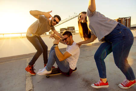Adult friends on terrace having fun while driving skateboardの写真素材
