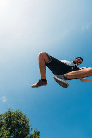 Parkour man exercising parkour jumping below sky