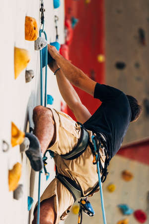 Man climber on artificial climbing wall in bouldering gymの写真素材