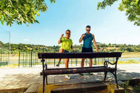 Sports man and woman doing stretching exercises on benchの写真素材