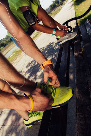 Fit couple tying their shoes and getting ready for running on riversideの写真素材