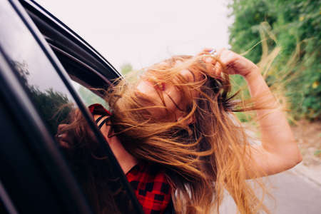 Wild girl riding around with her head out of the car window.の写真素材