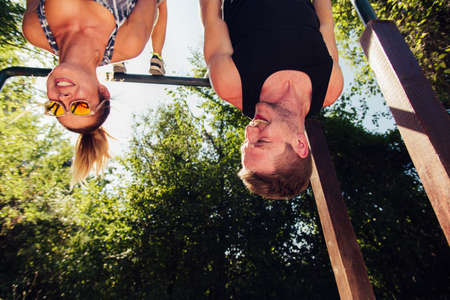 Strong man and athletic woman doing fitness and sport exercise in outdoor gymの写真素材