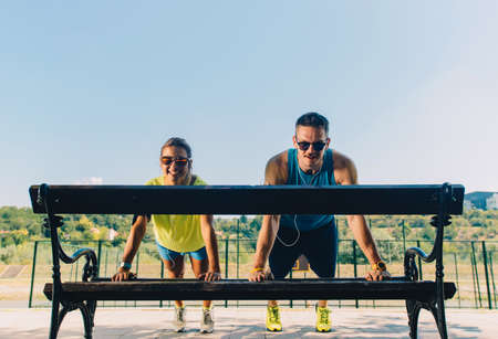 Sports man and woman doing stretching exercises on benchの写真素材