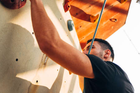 Young sporty man is bouldering in a climbing hall