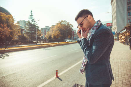 A young man is looking serious while is having a conversation on his mobile phone, near the city jamの写真素材