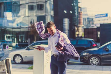 An urban young man is outdoors enjoying, while the wind is blowing his scarfの写真素材