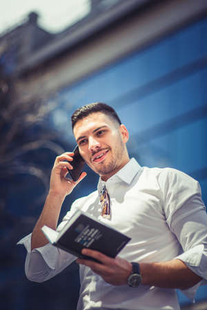 An urban young businessman is having a pleasant conversation in public and looking happyの写真素材