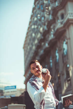 An urban businessman  is having a pleasant time, looking good while walking the street and showing his coffeeの写真素材