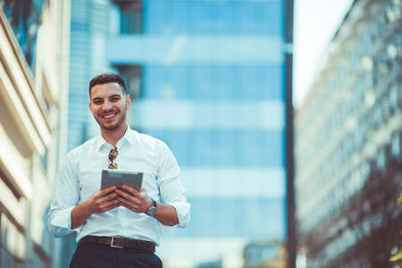 Business guy wearing white shirt is smiling and holding tabletの写真素材