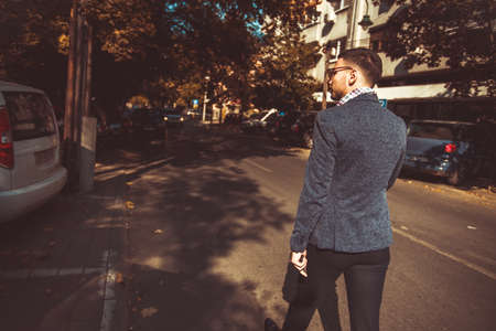 A young modern guy in suit is walking down the street and looking around