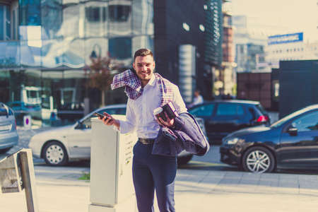 An urban businessman is outside on a windy day, holding notebook and phone and enjoying in the windの写真素材