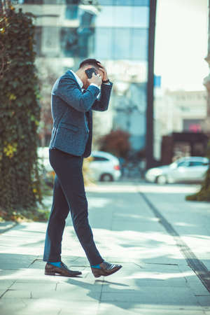 Nervous man is holding his hand stick to his head and arguing on cell phoneの写真素材