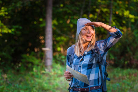 Young woman walking alone in the woods holding a map. Hiking concept in the mountain in summerの写真素材