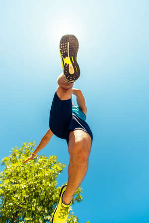Jogging sneakers while running against blue skyの写真素材