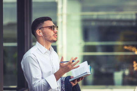 Modern caucasian man holding notebook and pen while listening musicの写真素材