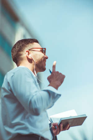 Modern caucasian man holding notebook and pen while listening musicの写真素材