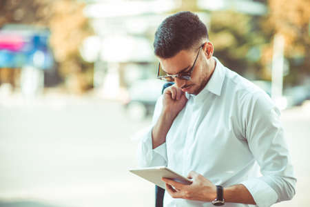 Business guy wearing white shirt is smiling and holding tabletの写真素材