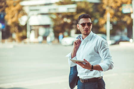 Business guy wearing white shirt is smiling and holding tabletの写真素材