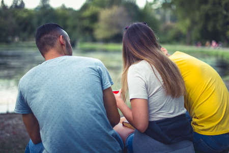 Three friends sitting in the park enjoying the view and having a conversationの写真素材