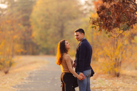 Young couple walking down the road filled with autumn leaves.の写真素材