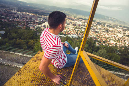 A man is enyoying the city panorama on a dangerous metal constructionの写真素材