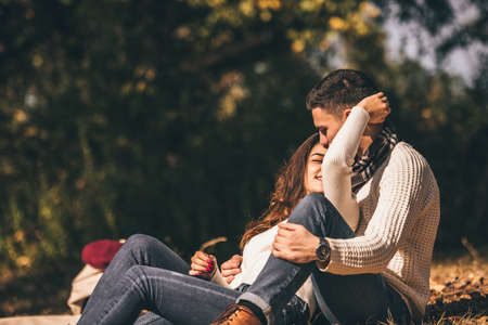 Splendid couple is smiling in the park and enjoying the sun and the river near themの写真素材
