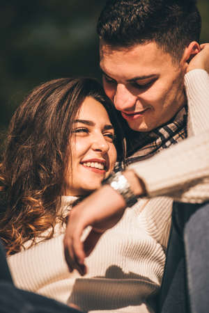 Lovely couple is lying in the park on autumn day, they are looking happy while huggingの写真素材