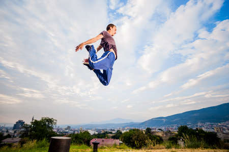 Caucasian man trains parkour while jump below blue skyの写真素材