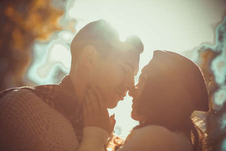 Pretty couple is enjoying the daily sunlight and kissing in the parkの写真素材