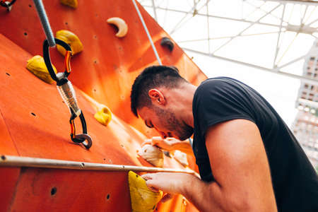 Young man practicing bouldering in outdoor climbing gymの写真素材