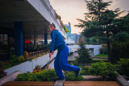 Adult man training parkour while running over obstacles