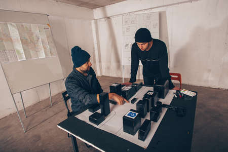 Two men sitting in a room and planning a robbery