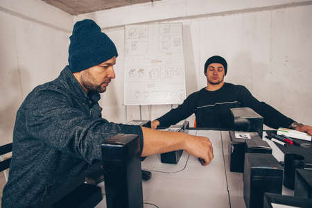 Young, male persons are sitting in a room, talking and preparing a heist