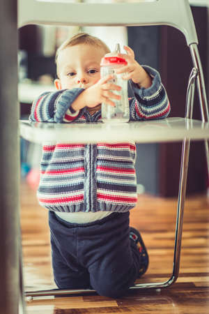 A beautiful baby is holding and looking in his empty bottleの写真素材