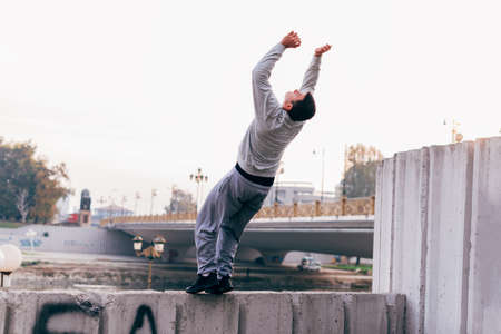 Young man practicing parkour at the city park,doing tricks and jumps.