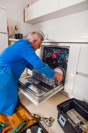 Plumbe in blue uniform fixing the household appliances in houseの写真素材