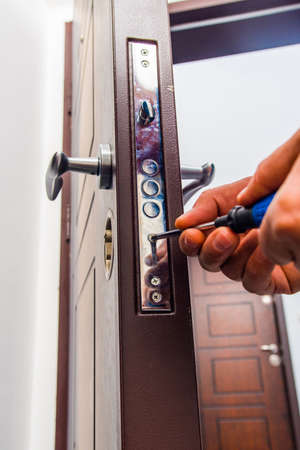 Professional worker is fixing the door lock in hallway