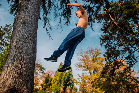Sportive guy try to running on tree in the parkの写真素材