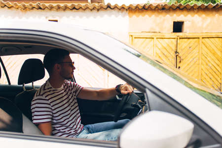 Man in his car in some neighborhood looking front of him