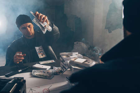 Gangsters are counting money in a smoky room with a gun near themの写真素材
